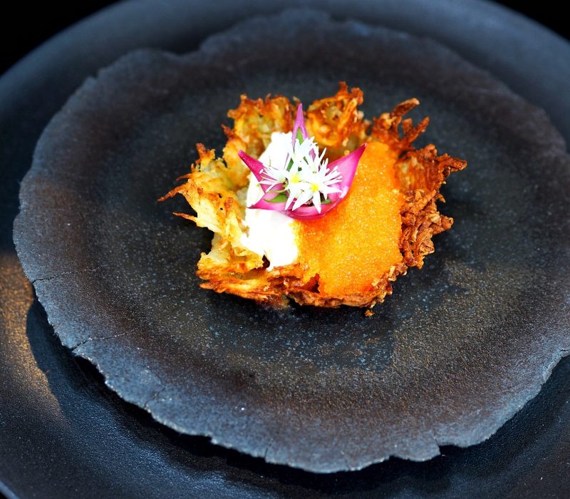 Crispy Nordic potato nest with roe, crème fraîche, and edible flowers – a gourmet canapé by a Norwegian luxury chef for elite yacht events.